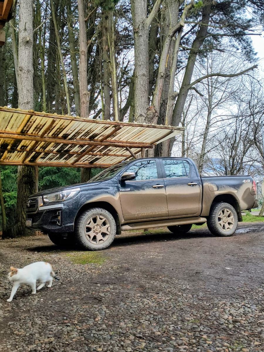 La Hilux 4x4 gris estacionada bajo el alero, lista para salir.