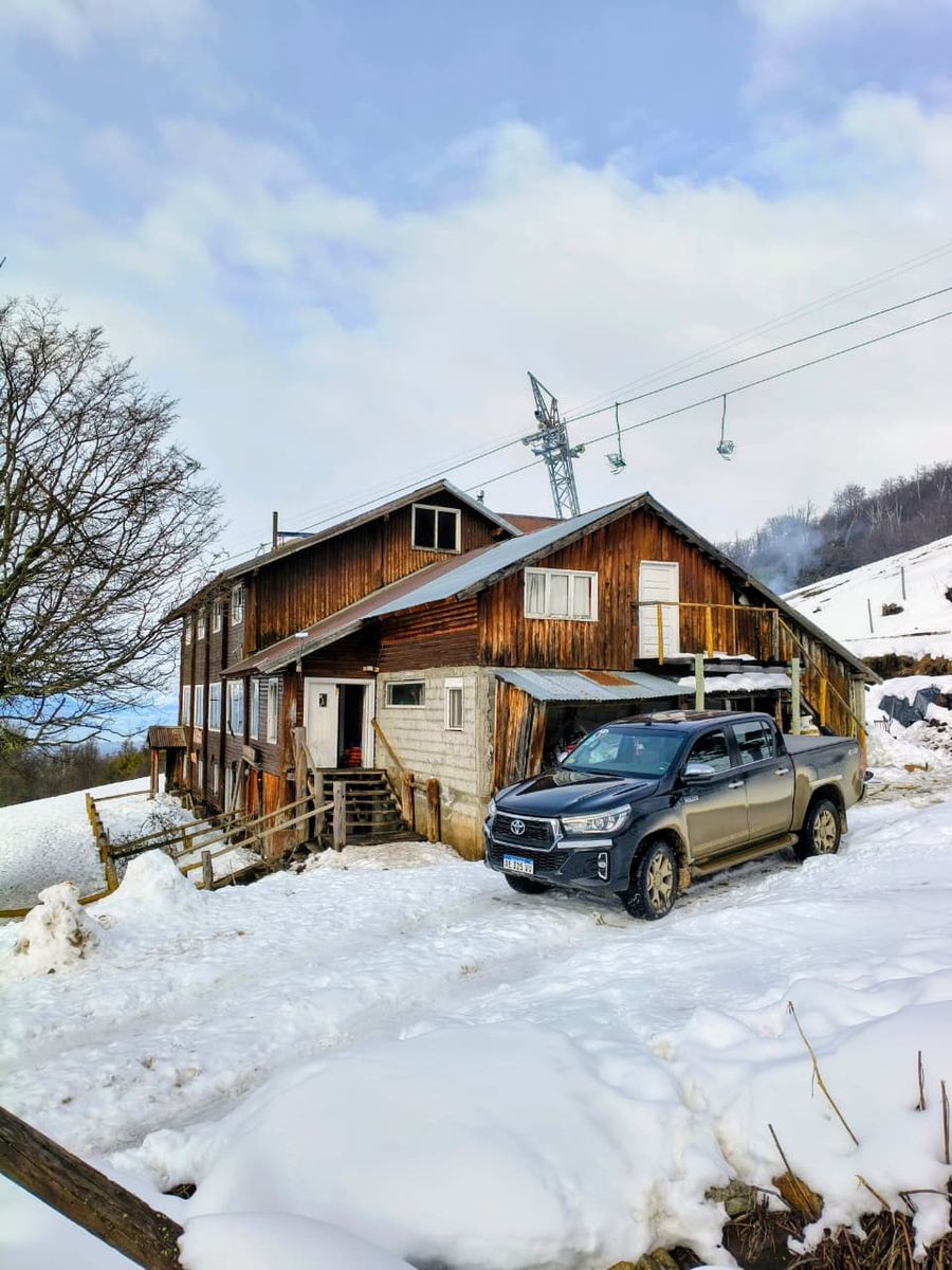 La camioneta estacionada en la nieve junto a un refugio de madera.
