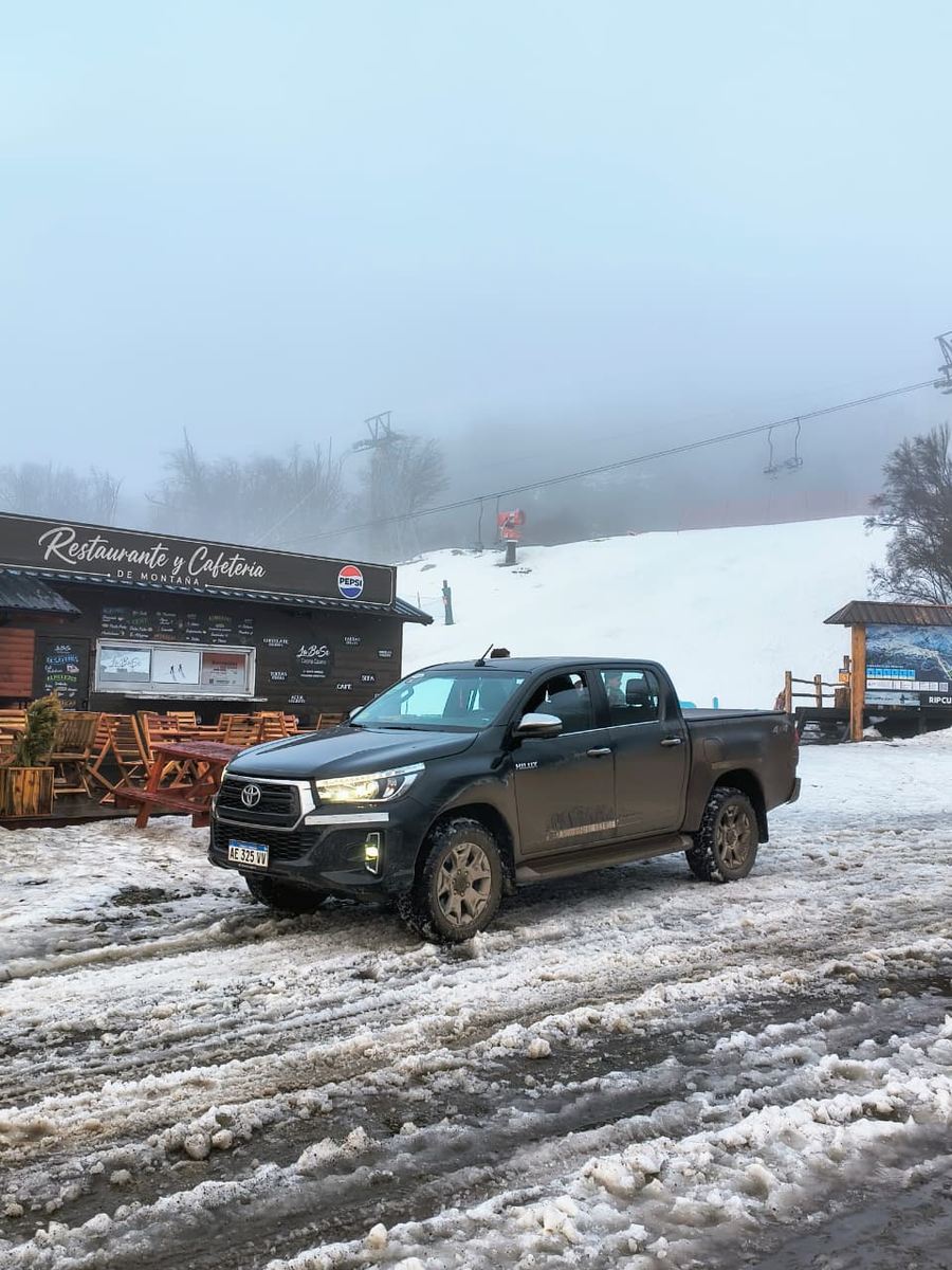 La Hilux en la base del cerro con niebla y nieve pisada.