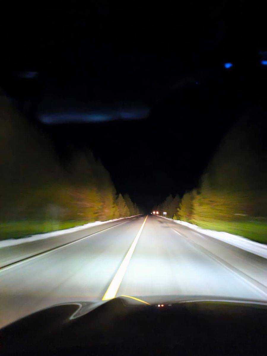 La ruta de noche desde la camioneta, con la nieve al costado.