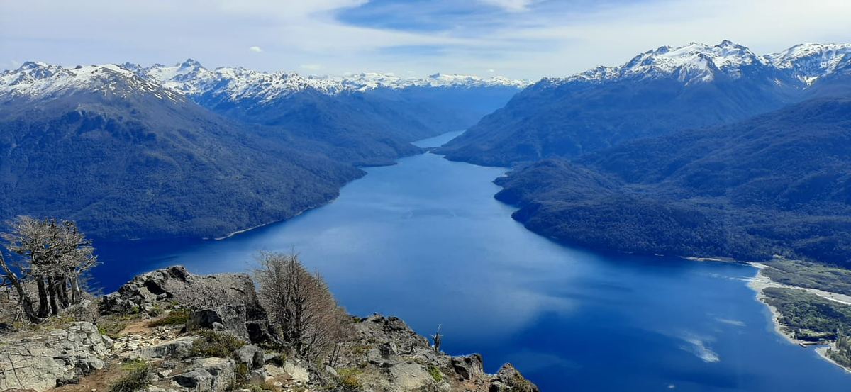 El lago Puelo desde la cumbre del Currumahuida, con los picos nevados.